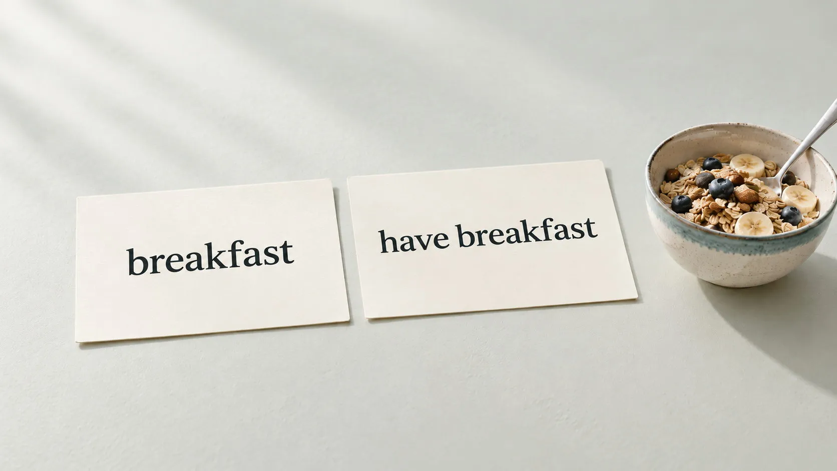 Dos tarjetas de estudio ilustrativas con las expresiones en inglés «breakfast» y «have breakfast», junto a un tazón de cereal y una cuchara.